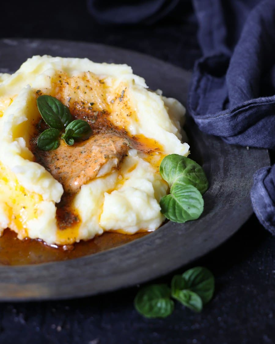 Mashed potatoes topped with gravy and fresh basil