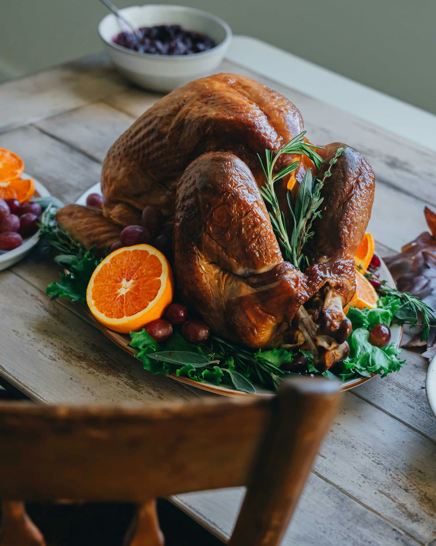 A golden roast turkey on a platter with orange slices and rosemary